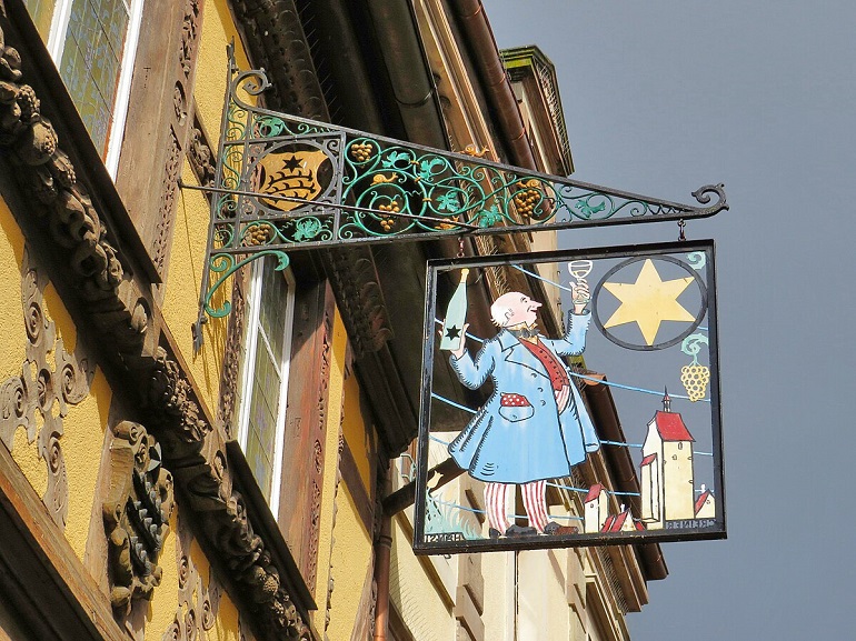 Traditional shop sign on Preiss-Zimmer House, Riquewihr (photo by Enric - CC BY-SA 4.0)