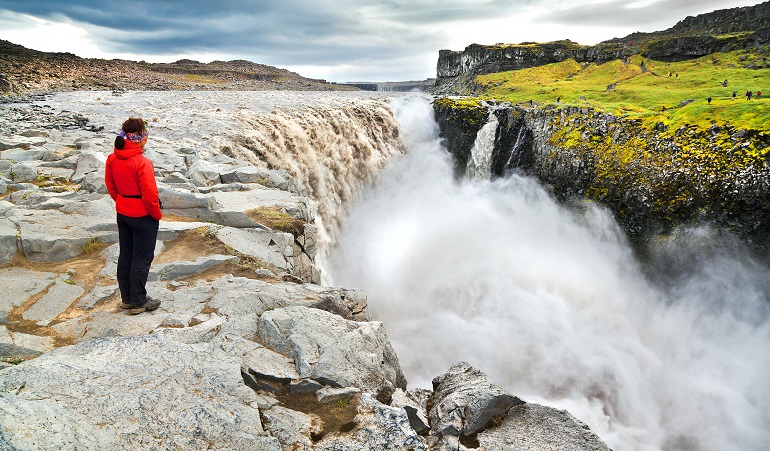 Woman standing near famous Dettifoss waterfall in Vatnajökull National Park (© minnystock | Dreamstime.com)